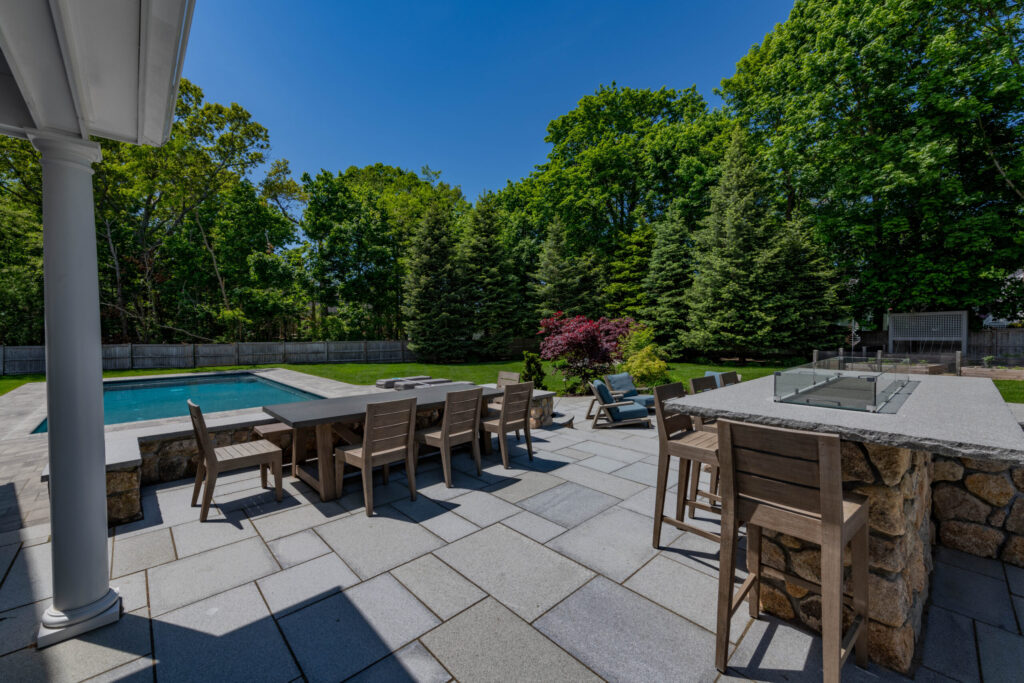 Picture of pool with patio, firepit and outdoor kitchen. Example of Landscape Design and Construction in Duxbury, Massachusetts